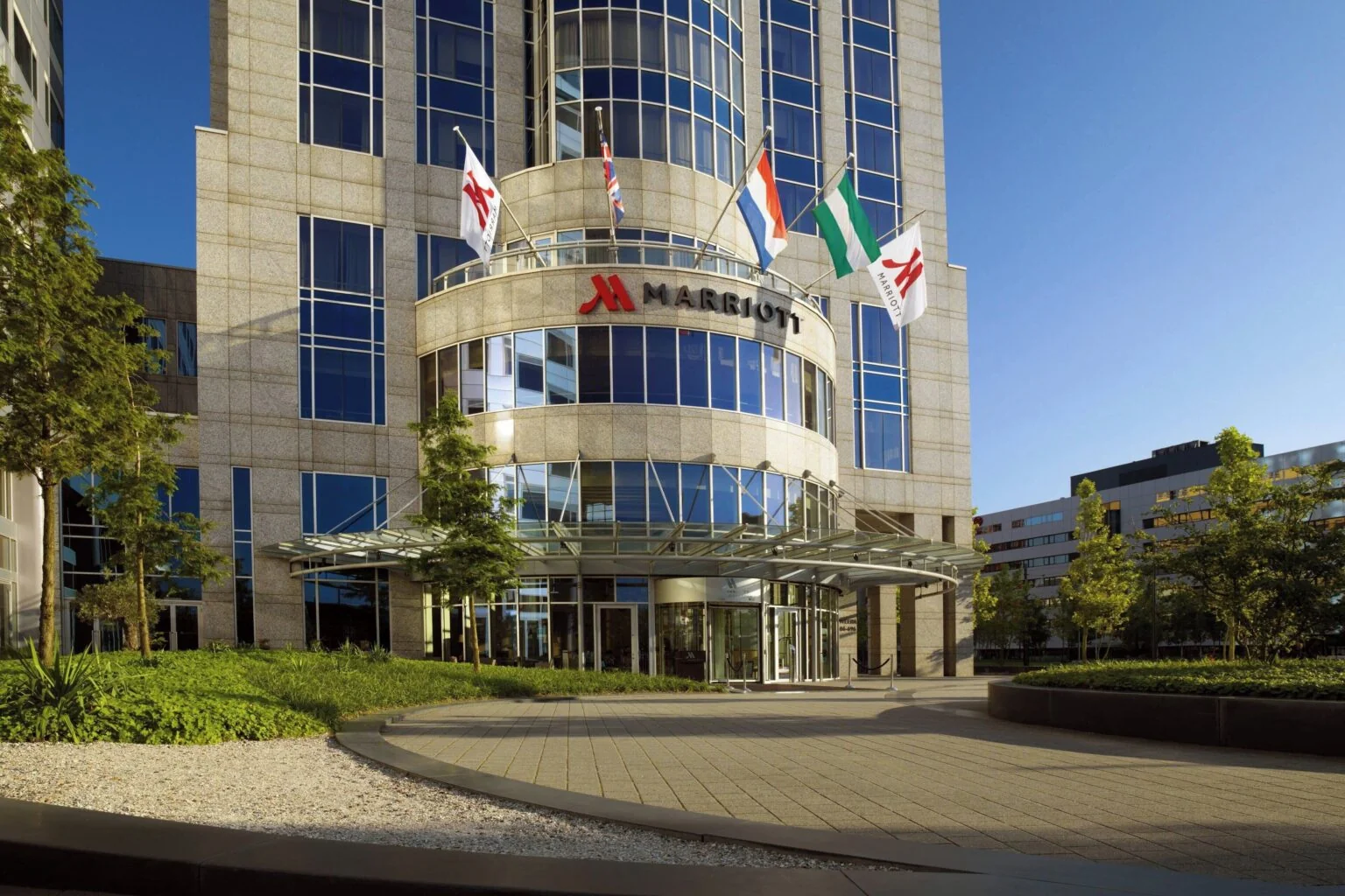 Exterior facade and entrance of the Rotterdam Marriott Hotel tower, with international flags at the main entrance