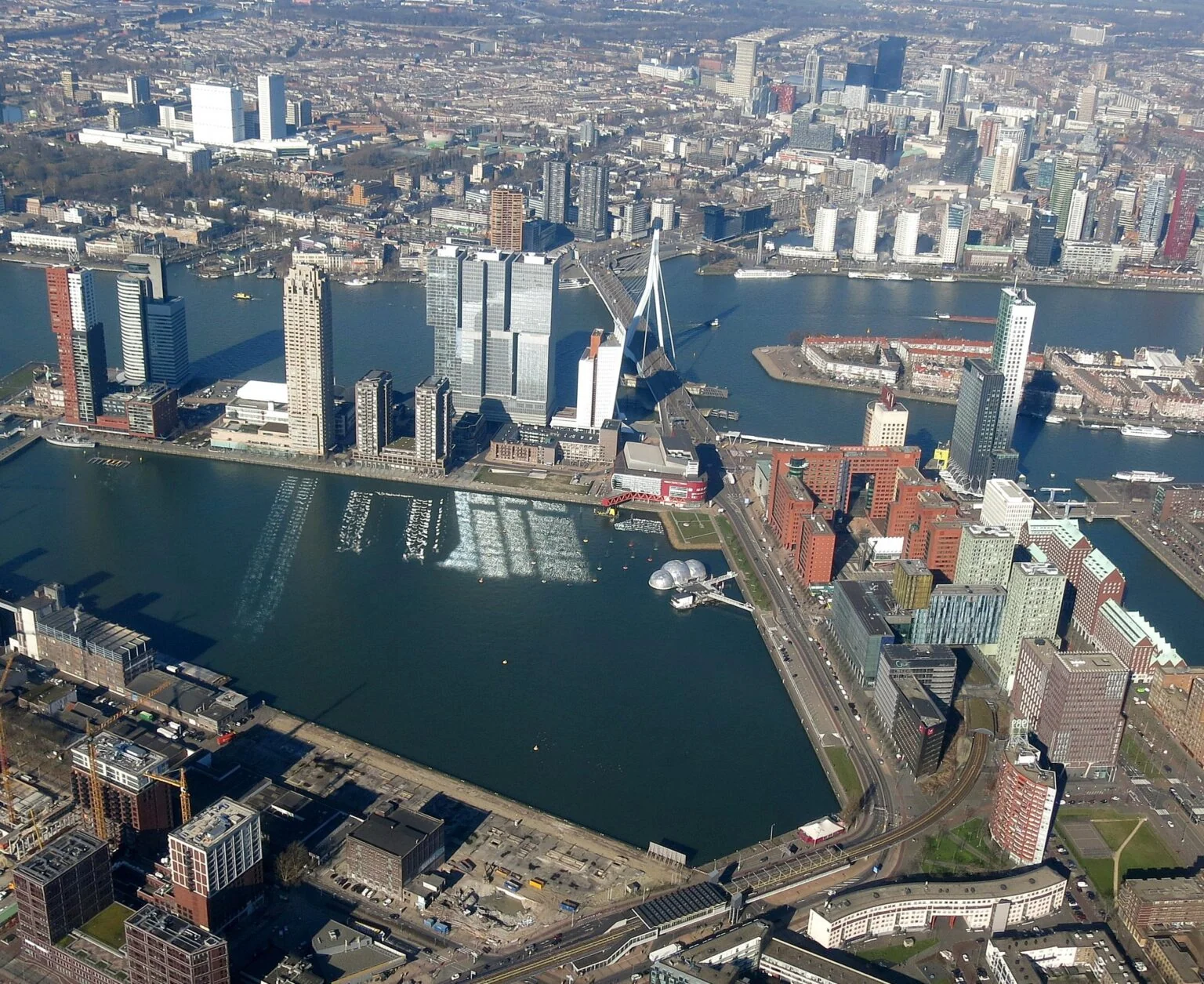 Aerial view of Rotterdam's skyline and harbour, including the Erasmus Bridge and the Kop van Zuid towers