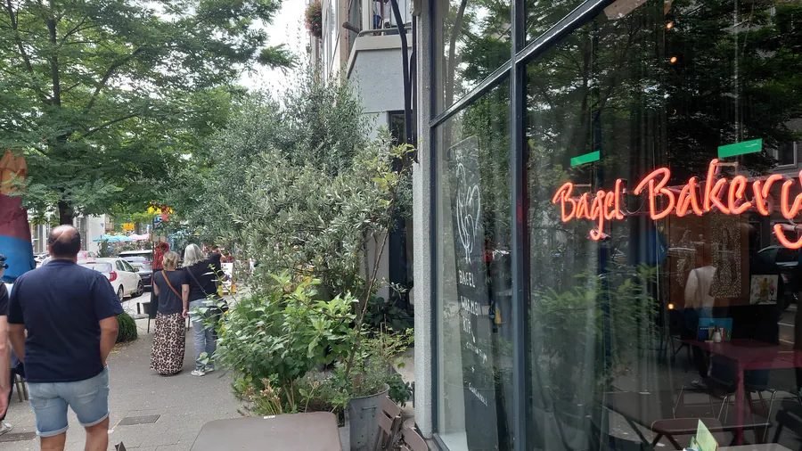 Tree-lined street in Rotterdam's Witte de Withstraat district, with a bakery storefront and pedestrians Tree-lined street in Rotterdam's Witte de Withstraat district, with a bakery storefront and pedestrians